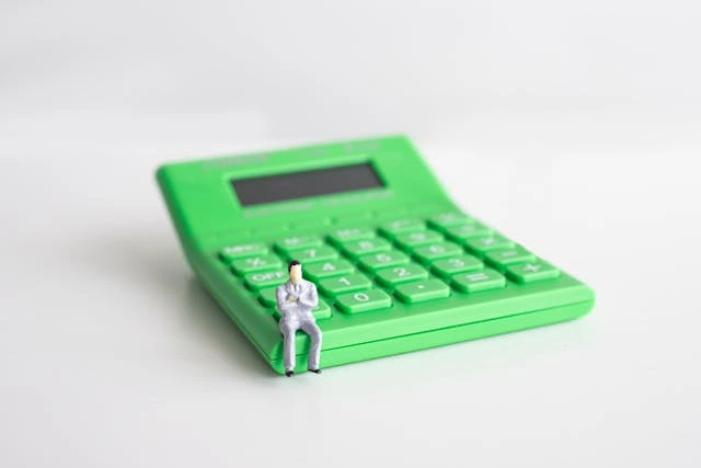 une calculatrice verte et un petit bonhomme posé dessus